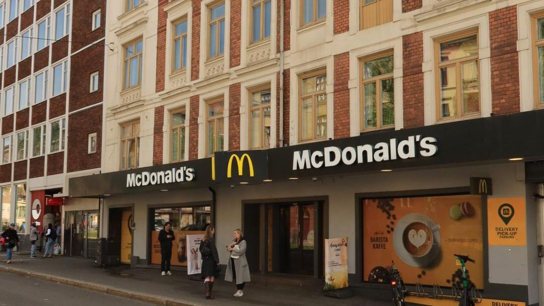 Fasade av McDonald’s i bygård med folk utenfor og plakater for kaffe i vinduene.